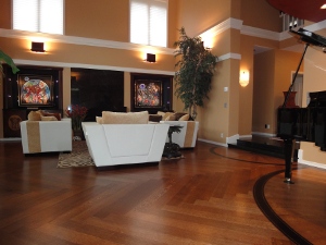 Elegant living room featuring refinished hardwood floors, modern white furniture, decorative plants, and stained glass accents, highlighting the beauty of wood floor restoration services.