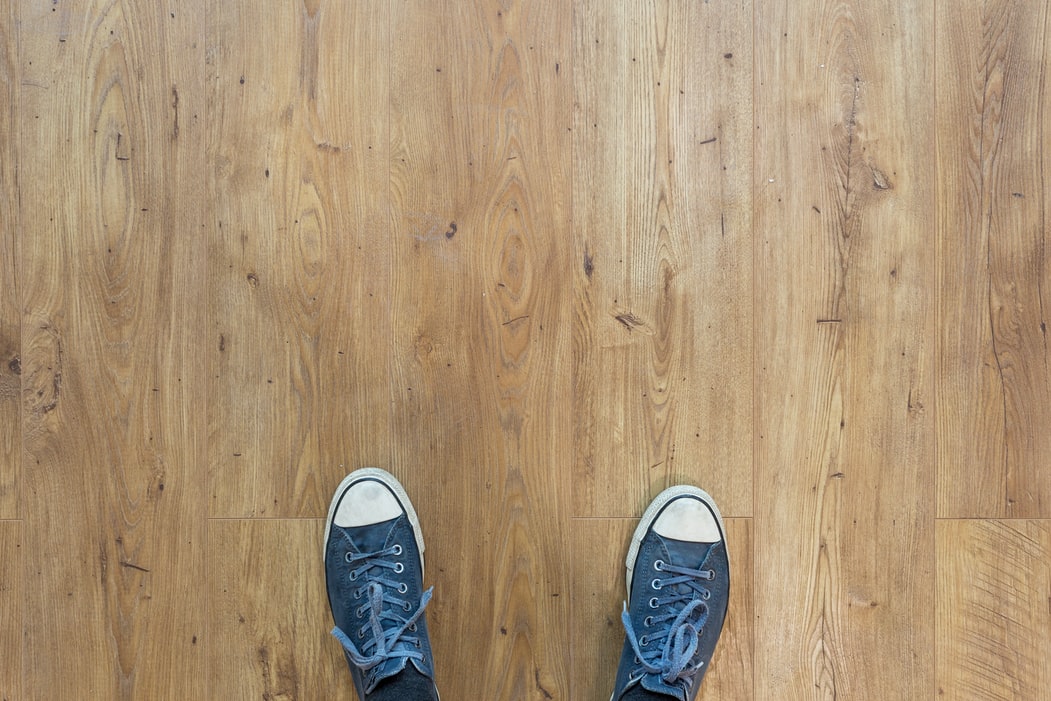 Luxury Vinyl vs Hardwood - Pros and Cons 1 person wearing blue-and-white low-top sneakers