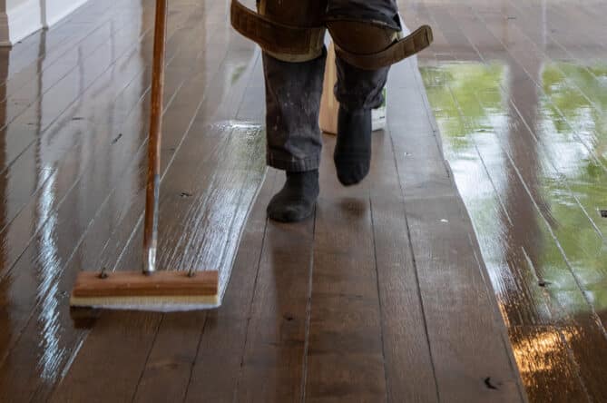 A hardwood flooring professional applies finish during the dustless refinishing process. Contact SVB Wood Floors to learn more about refinishing wood floors in Kansas City