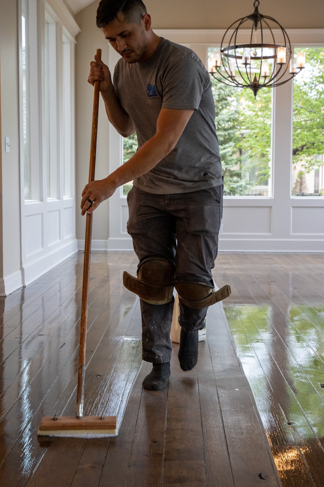 A hardwood flooring professional applies finish during the dustless refinishing process. Contact SVB Wood Floors to learn more about refinishing wood floors in Kansas City