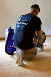 flooring contractor connecting a hose to a dustless refinishing containment system