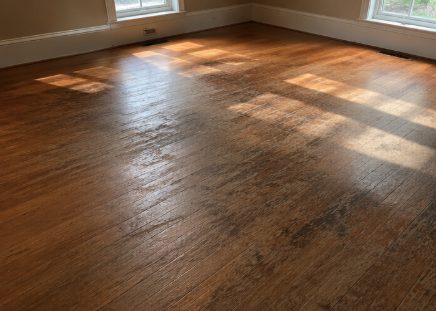 Dull and faded hardwood floors showing signs of wear and discoloration.