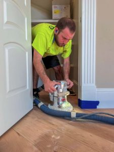 SVB worker doing dustless hardwood refinishing in a pantry entry.